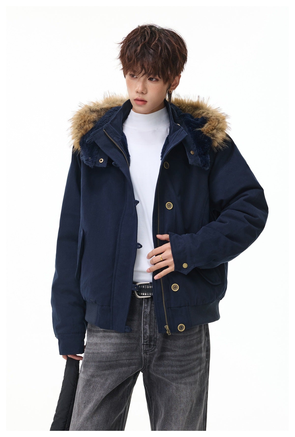 Close view of a model in a navy hooded jacket with tan fur trim, dark lining, and brass-tone buttons.