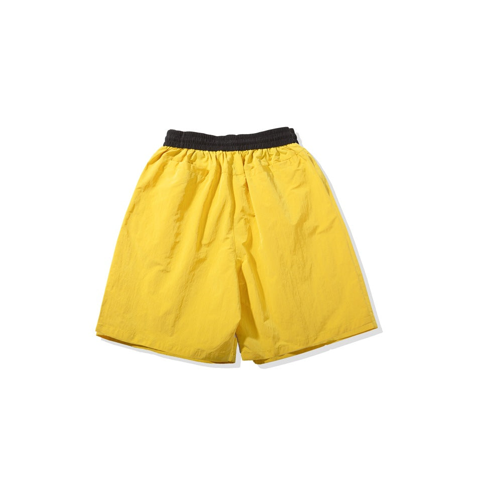 Back view of yellow shorts with a black elastic waistband and two rear pockets.