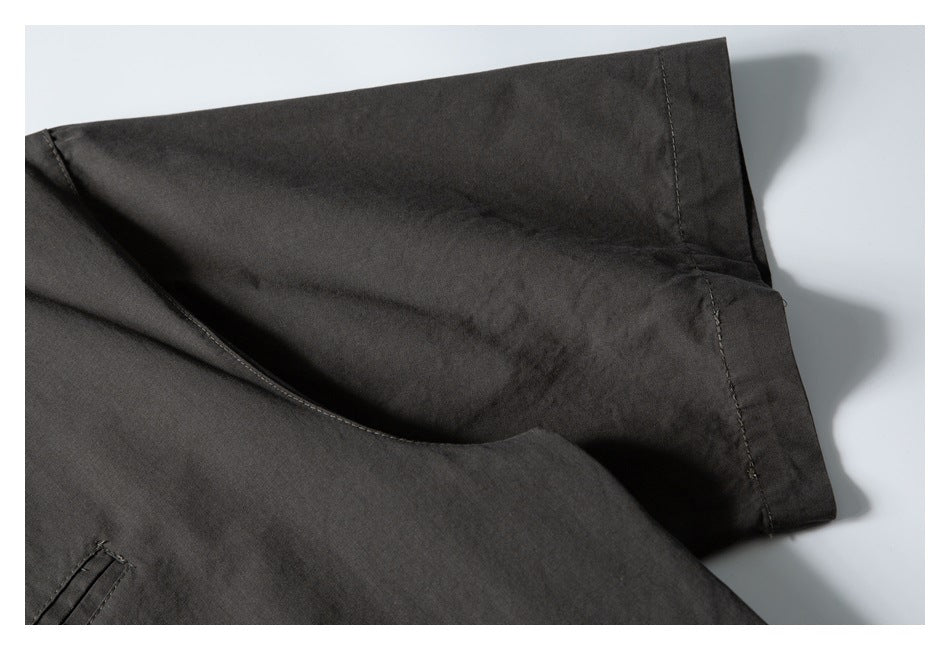 Close-up of dark charcoal garment fabric with an overlapping seam and stitched edge.