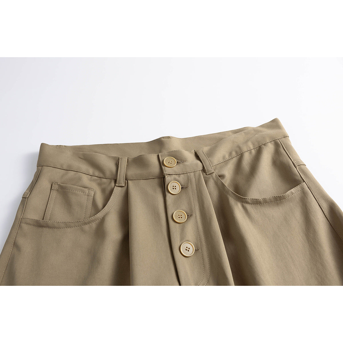 Close-up of taupe wide-leg trousers showing the waistband, front pockets, belt loops, and four-button fly.
