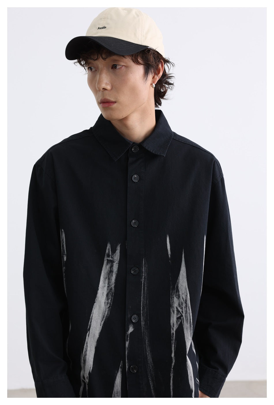 Model wearing a black button-up shirt with white brushstroke graphics across the lower front.