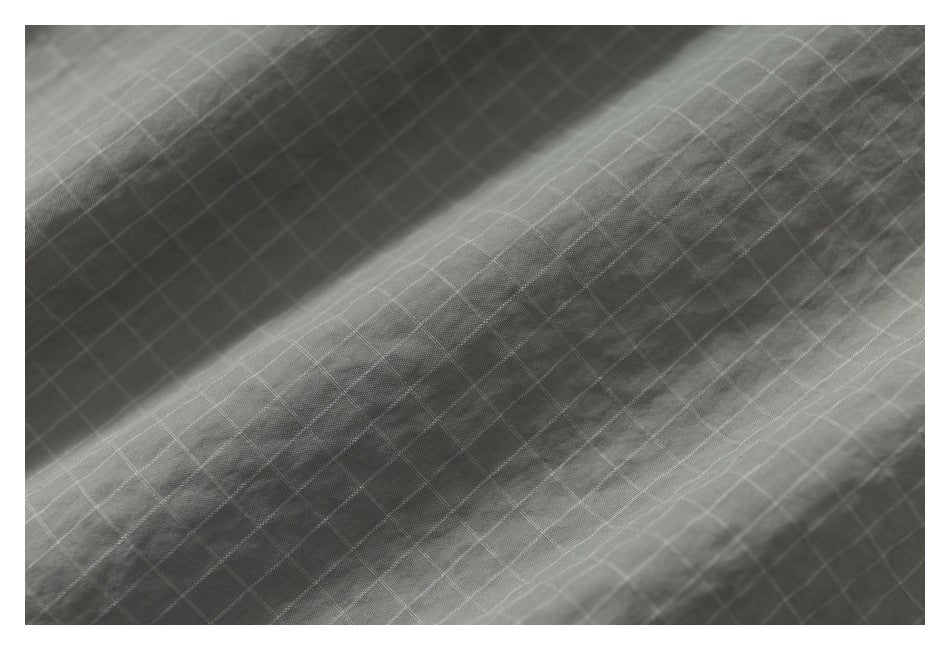 Close-up of gray fabric with a fine white grid pattern and soft folds.