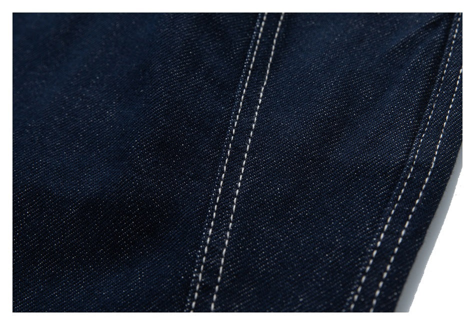 Close-up of dark indigo denim with parallel rows of light contrast stitching.