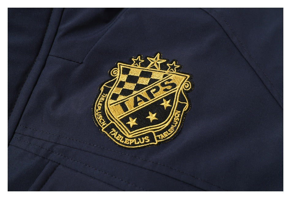 Close-up of a gold embroidered crest on navy jacket fabric.