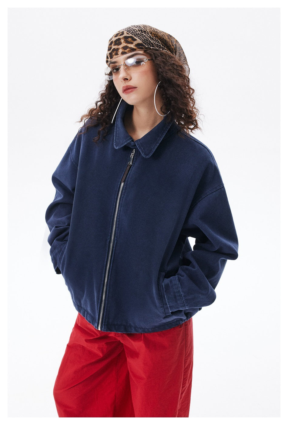 Angled upper-body view of a person wearing an oversized navy jacket with a pointed collar and front zipper.