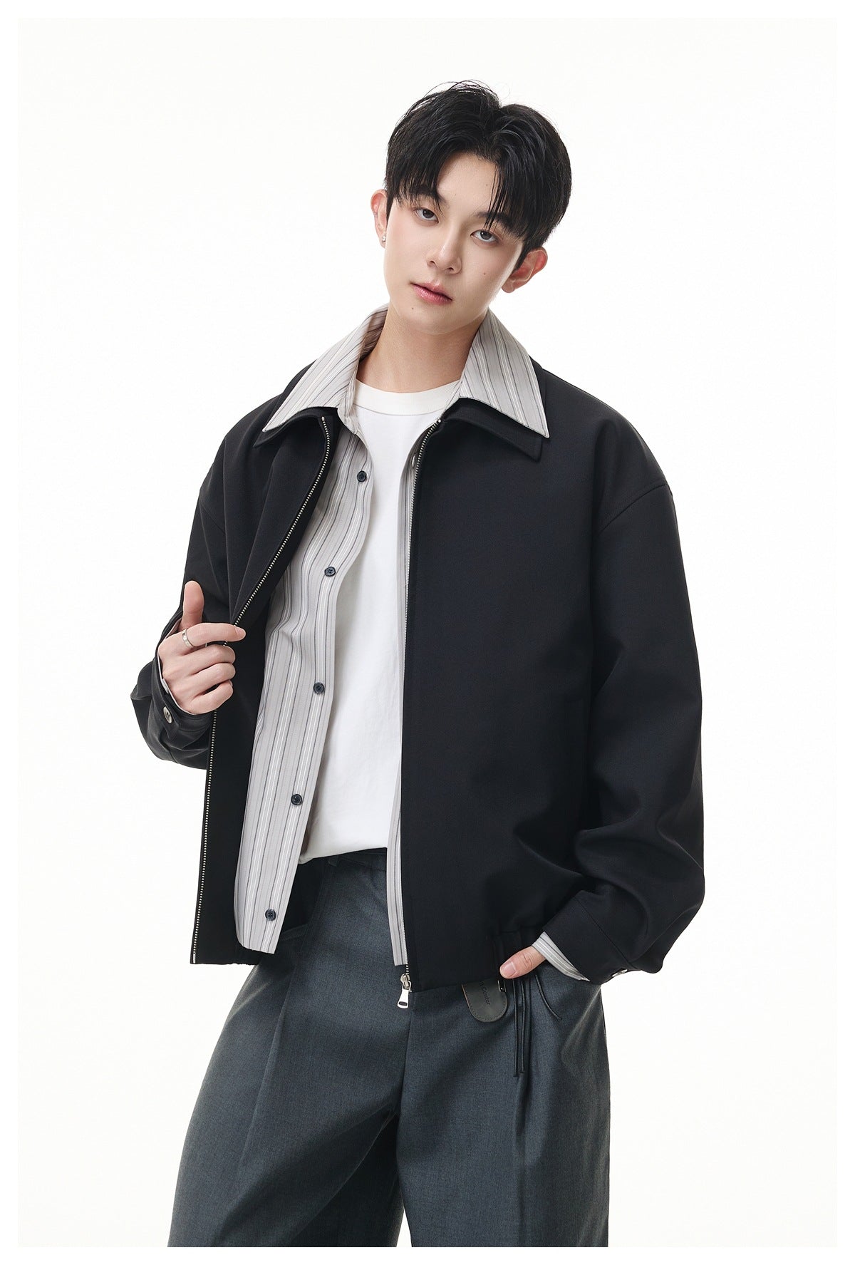 Model showing an open black zip jacket with a wide collar over a gray striped shirt and white tee.