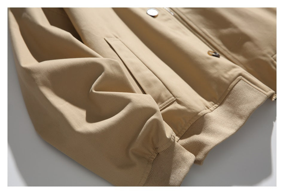 Close-up of the tan jacket's sleeve, cuff, front pocket, and lower hem.