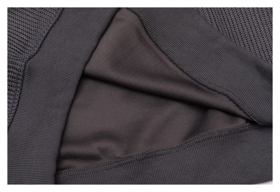 Close-up of a charcoal-gray knit garment showing its inner fabric and ribbed edge seam.