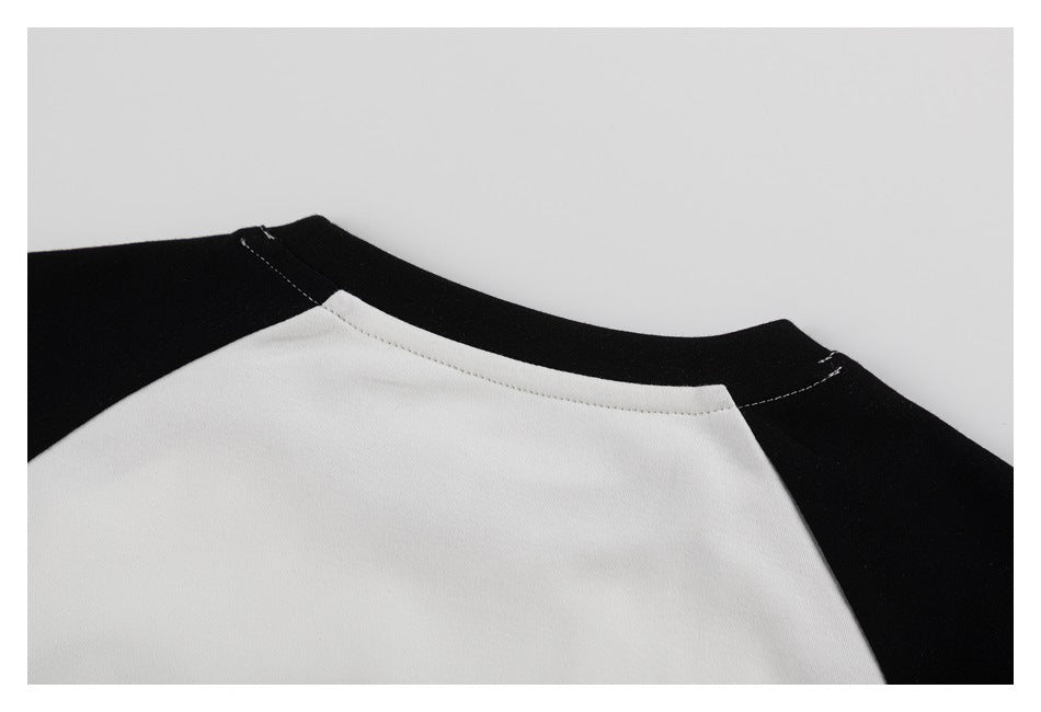 Close-up of a white shirt neckline and shoulder with contrasting black raglan panels.