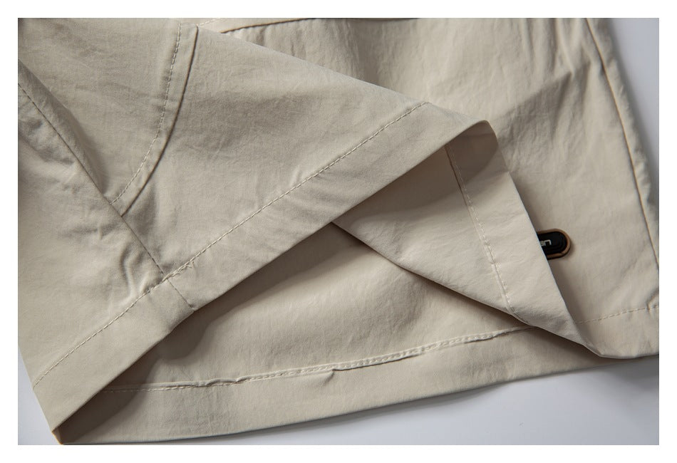 Close-up of cream shorts showing folded fabric, stitched seams, and a small dark garment tag.