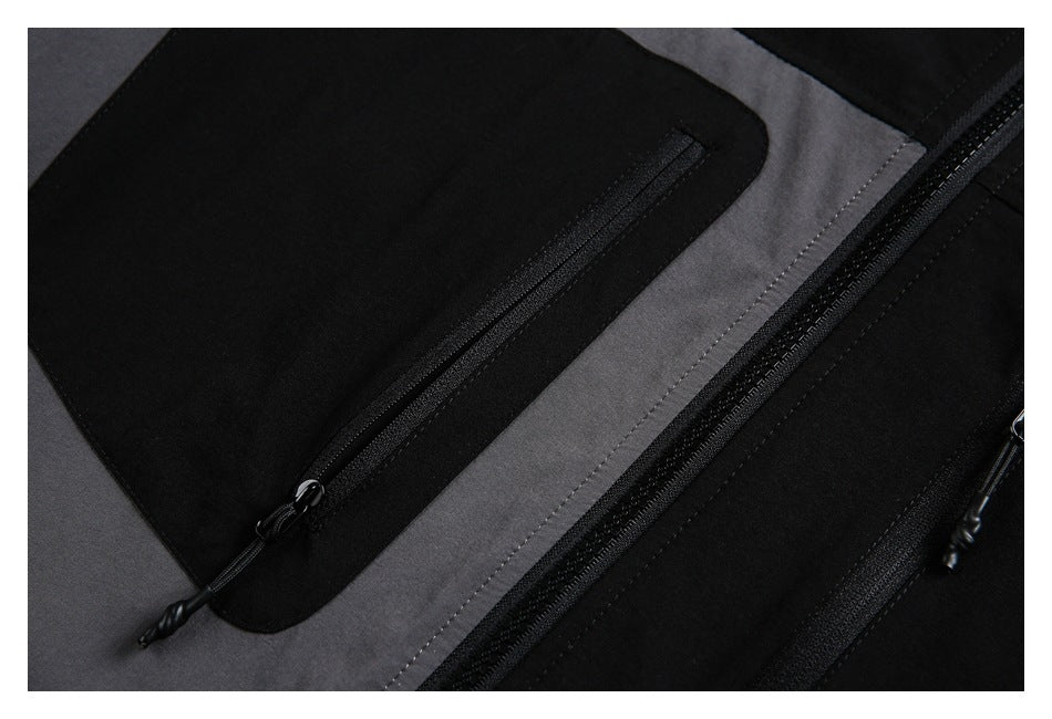 Close-up of a black zippered chest pocket, central zipper, stitching, and gray color-block panel.