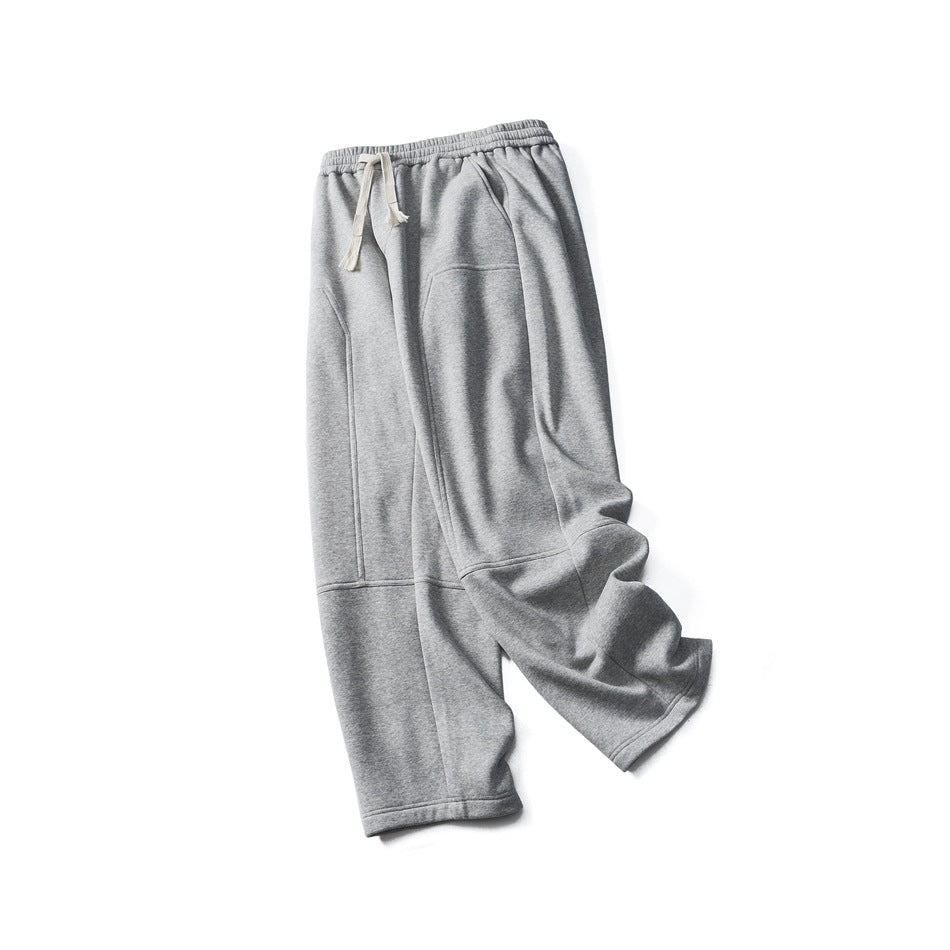 Full view of gray sweatpants laid flat, with an elastic waist, cream drawstrings, and a large front pocket.