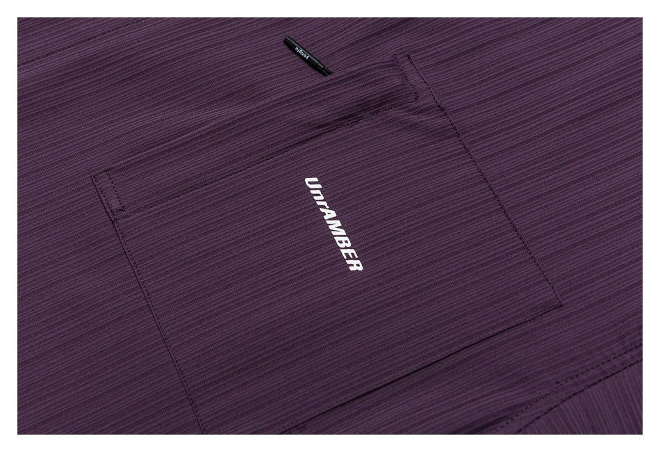 Close-up of the plum-purple shirt's chest pocket, ribbed texture and white UNRAMBER lettering.