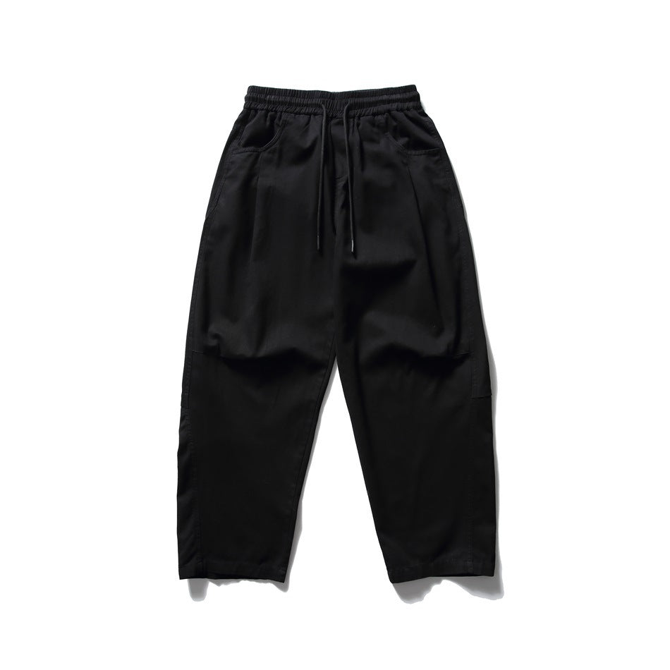 Black wide-leg pants with elastic drawstring waist and slanted front pockets, flat lay front view