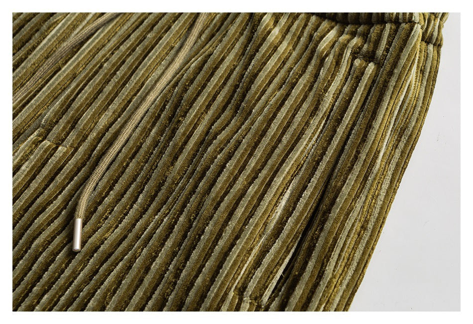 Close-up of olive and tan striped corduroy fabric with a small metal drawstring tip.