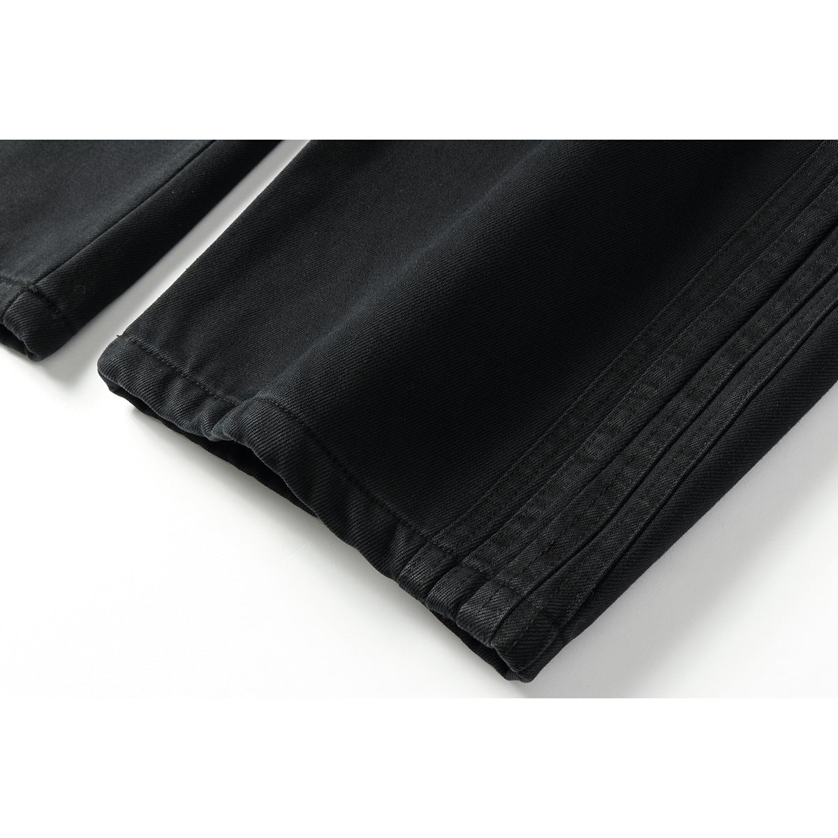 Close-up of the wide, double-stitched hems on black pants.