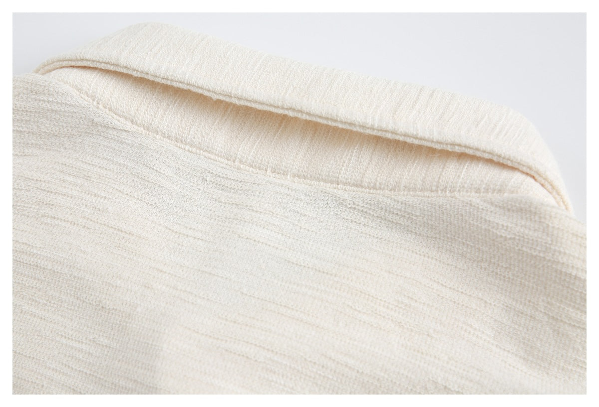 Close-up of an ivory knit garment with a broad folded ribbed edge.