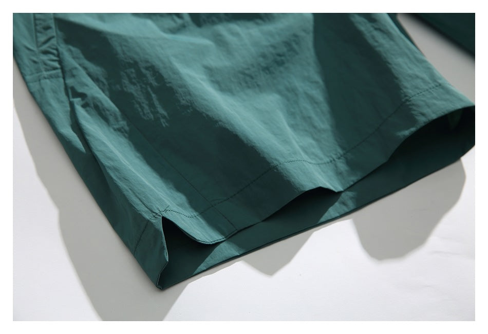 Close-up of the hem and stitching on teal shorts against a white background.