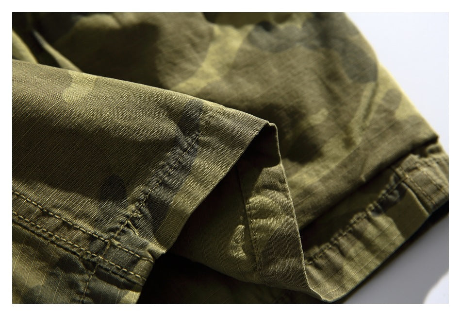 Close-up of the stitched hem and folded edge on olive camouflage shorts.
