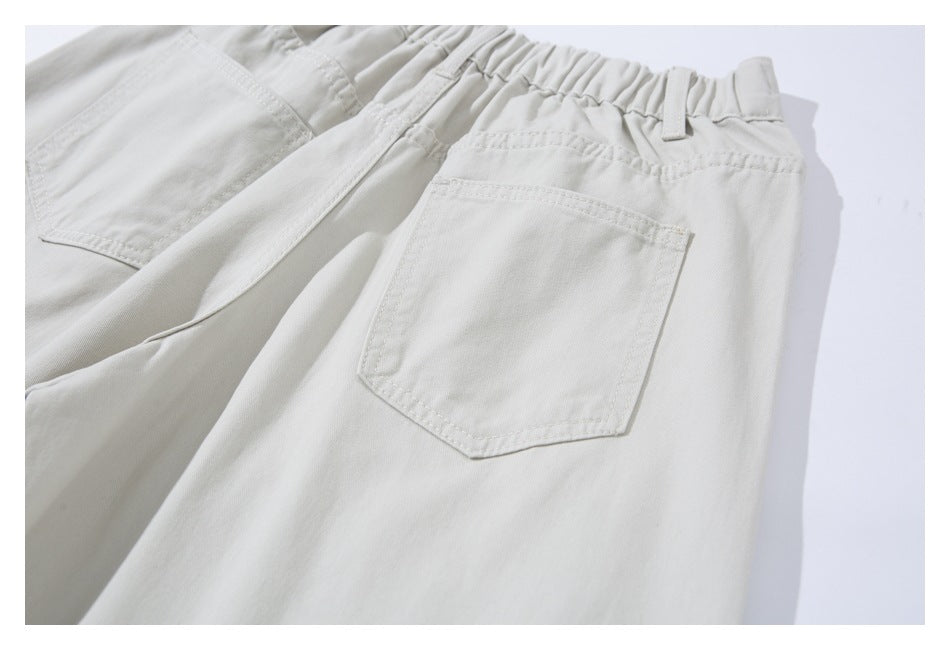 Close-up of ivory trousers showing an elastic waistband, belt loops, and a back patch pocket.