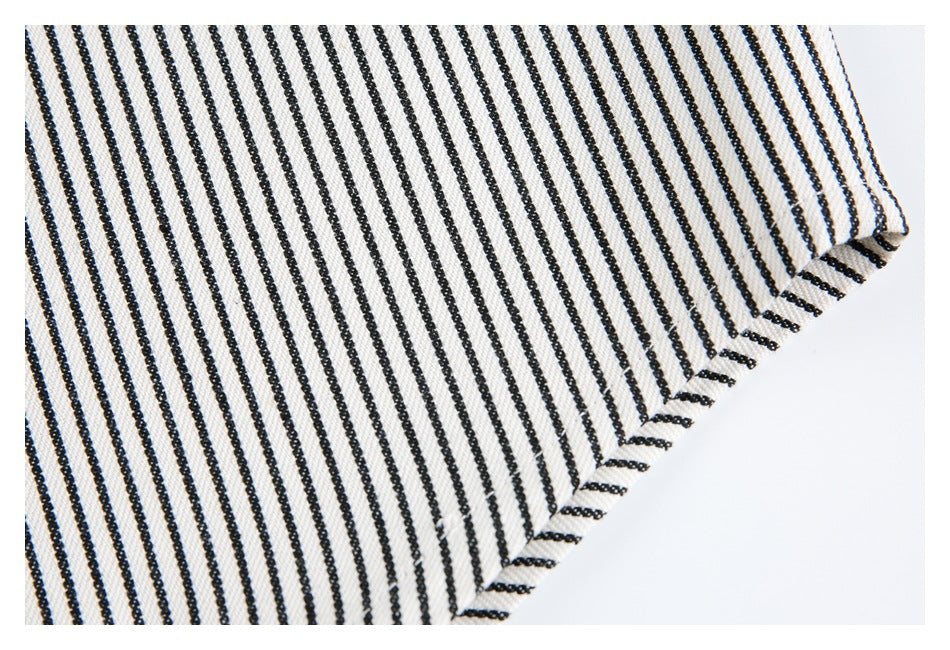 Close-up of the finished edge of cream fabric with narrow black stripes.