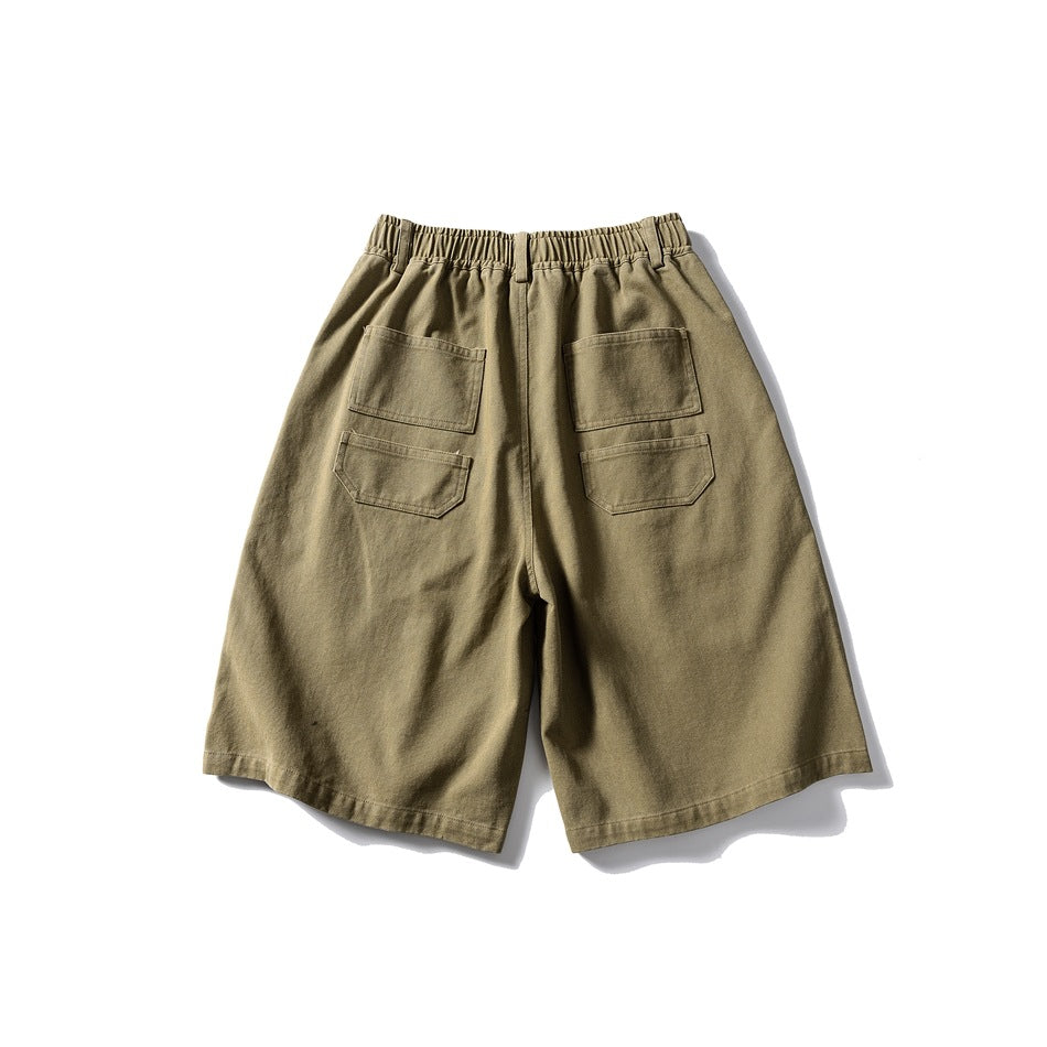 Back view of olive-khaki shorts with an elastic waistband and four patch pockets.