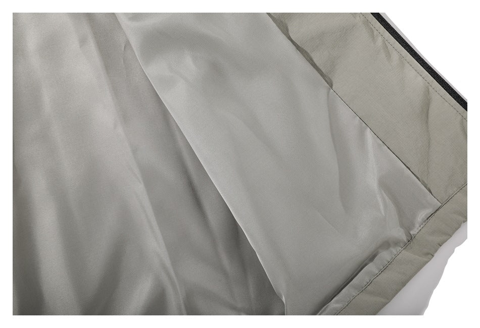 Close-up of light gray jacket fabric with diagonal seam lines and a dark edge trim.