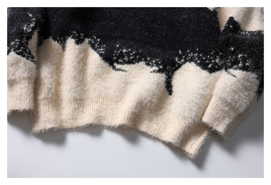 Close-up of the ivory ribbed hem and sleeve cuffs below the black-and-ivory pattern of a fuzzy knit sweater.