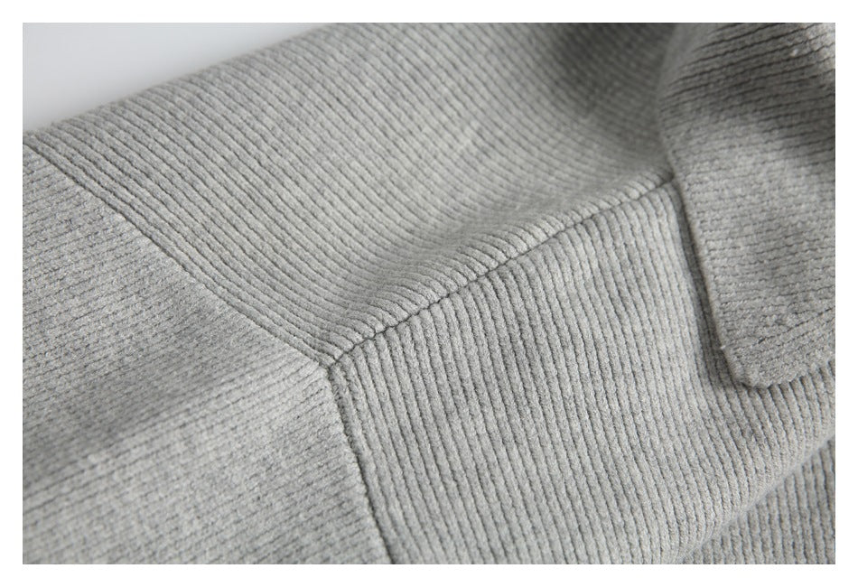 Close-up of a seam joining ribbed sections of a light gray knit garment.