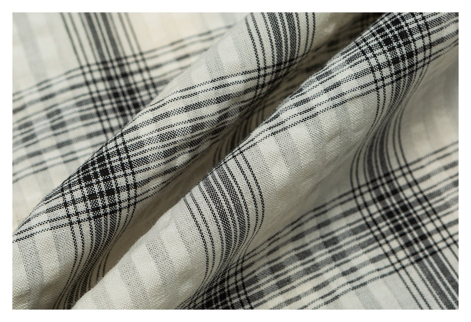 Close-up of cream fabric with a black plaid pattern and visible weave.