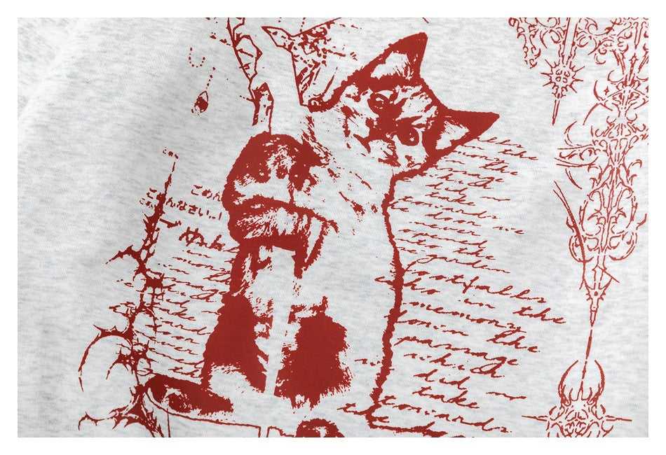 Close-up of the sweatshirt’s red cat illustration and decorative script printed on light gray fabric.