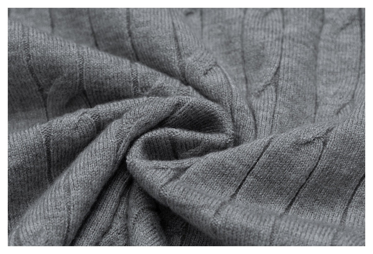Close-up of folded gray knit fabric showing its textured cable pattern and stitches.