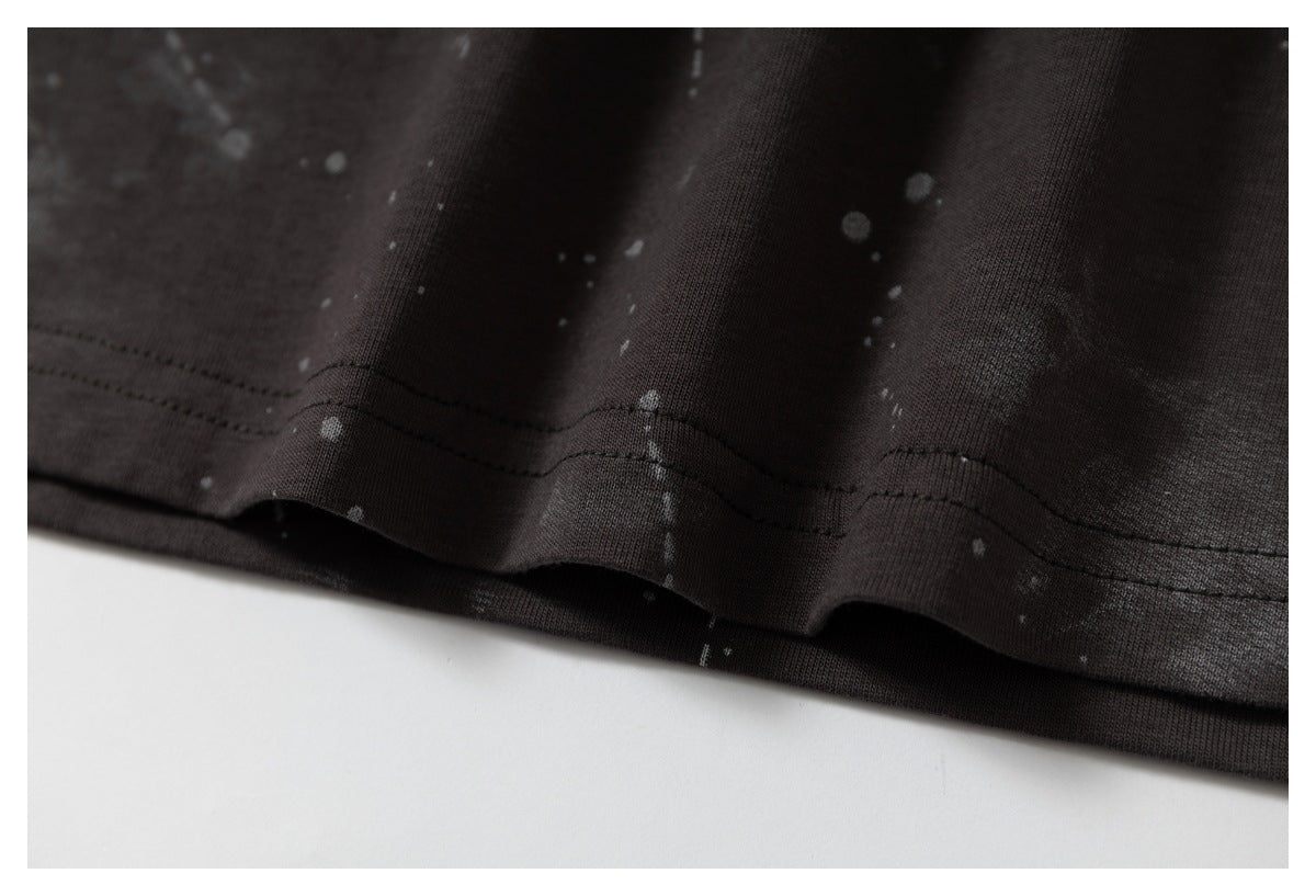 Close-up of the stitched hem on dark fabric with a subtle gray splatter pattern.
