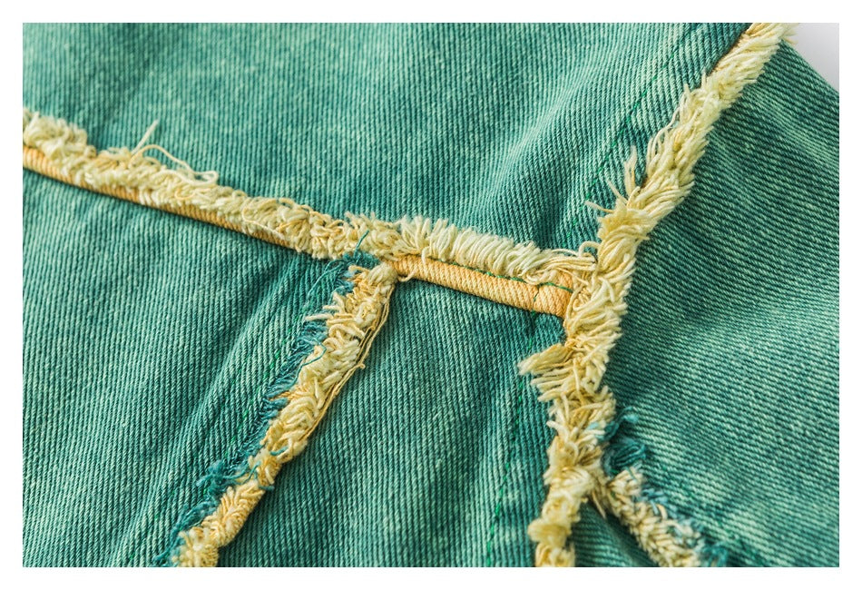 Close-up of teal denim seams with mustard-yellow stitching and thick, frayed raw edges.