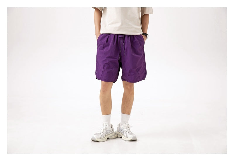 Front view of a person wearing purple knee-length shorts with a white T-shirt.