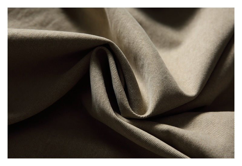 Close-up of taupe-gray fabric draped in soft folds, showing its fine diagonal weave.