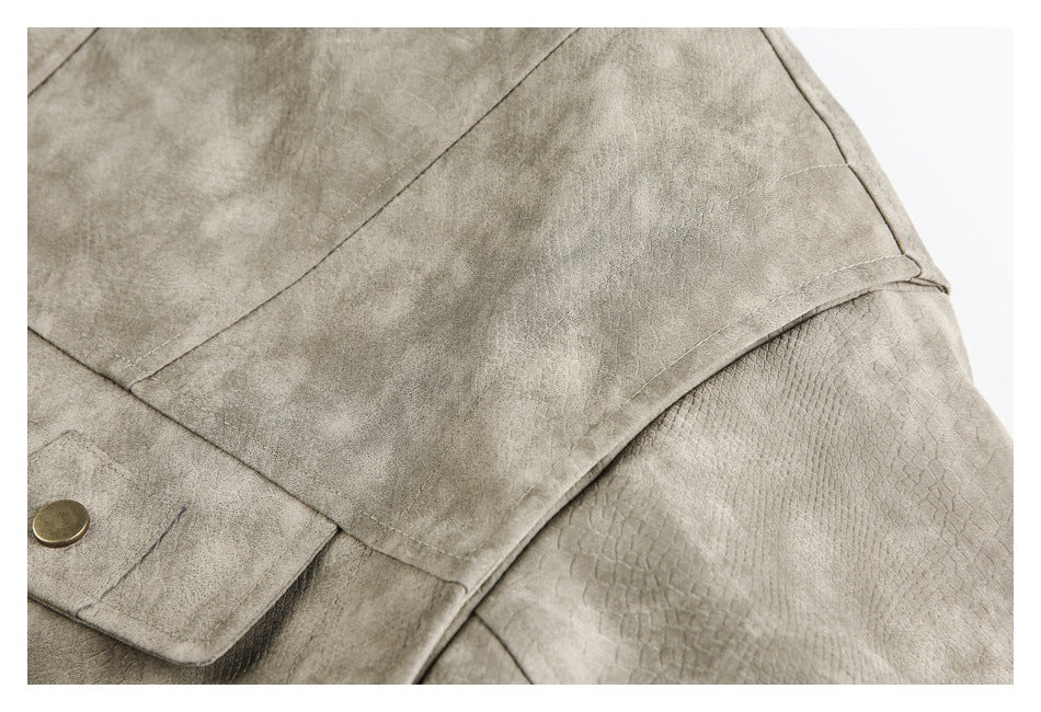 Close-up of a taupe-gray jacket panel with stitched seams and a subtle reptile-like embossed texture.