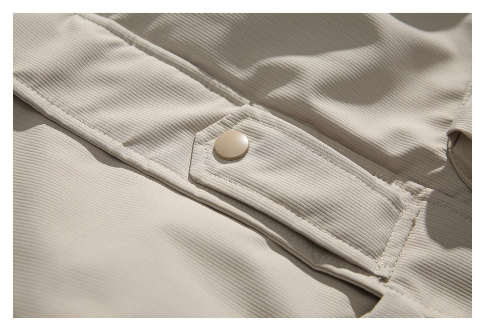 Close-up of a beige snap button and stitched front placket on the jacket.