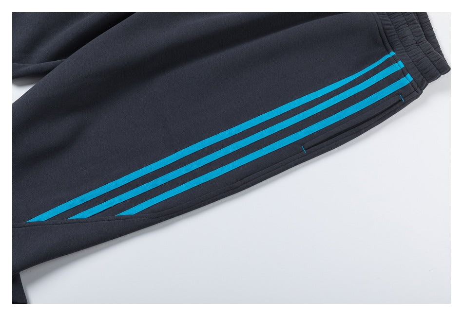 Close-up of charcoal jogger pants with three bright blue stripes along the leg and an elastic cuff.