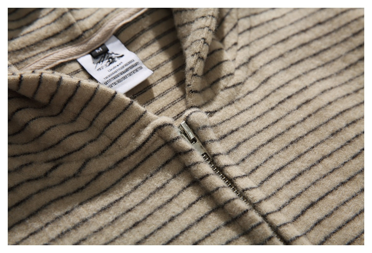 Close-up of the metal zipper and thin dark stripes on beige fabric.