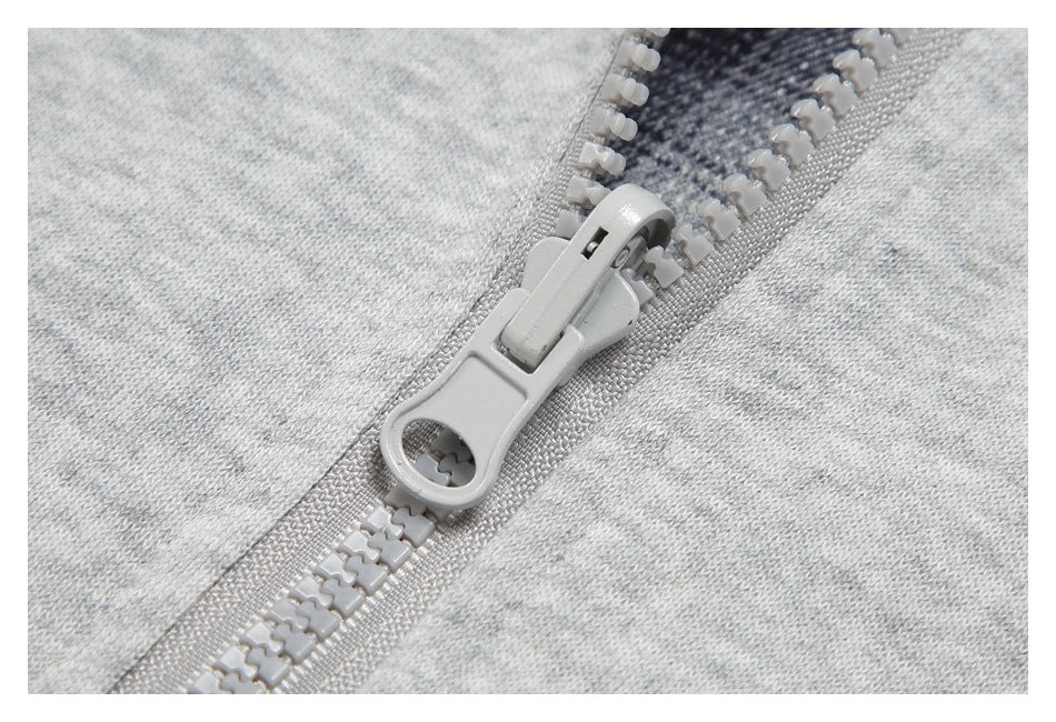 Close-up of a light gray zipper pull and teeth against heather-gray fabric.