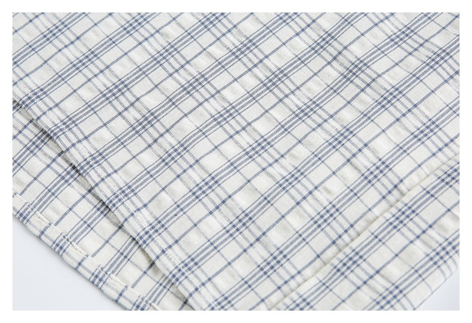 Close-up of the lower edge and stitching on a blue-gray plaid shirt.