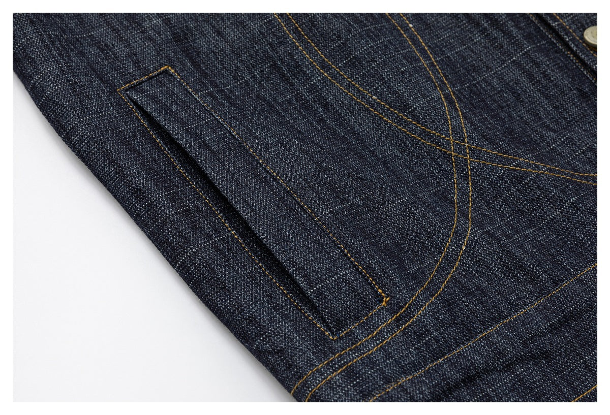 Close-up of a narrow stitched pocket on dark indigo denim with ochre seams.