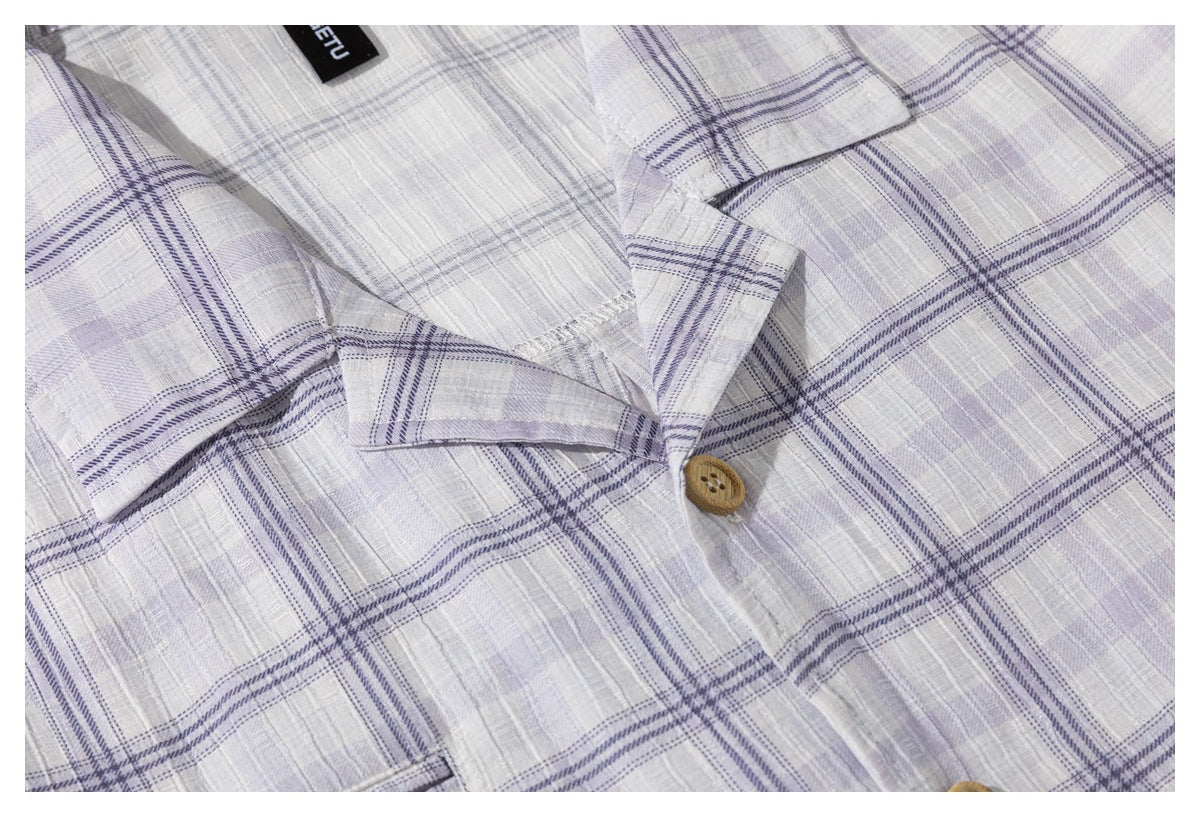 Close-up of a light gray-lavender plaid shirt collar, placket, tan button, and partial black neck label.