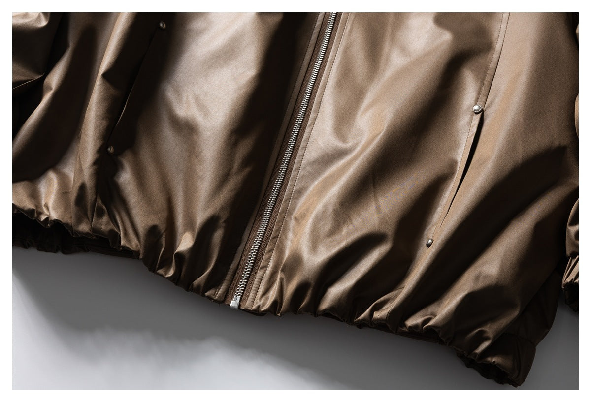 Close-up of the brown jacket's front zipper, snap-button pockets and gathered hem.