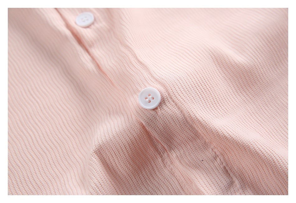 Close-up of a white four-hole button on pale pink ribbed fabric.