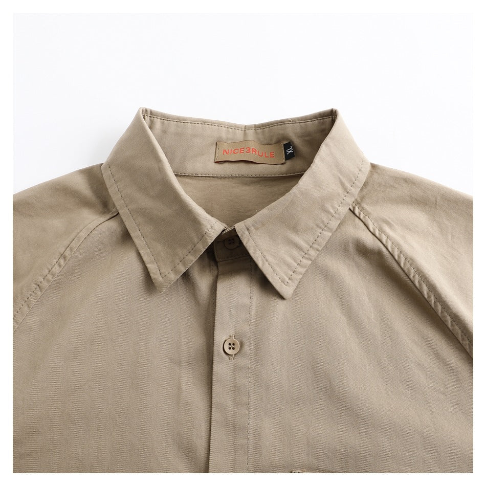 Close-up of a beige collared shirt neckline, front button, and sewn brand label.