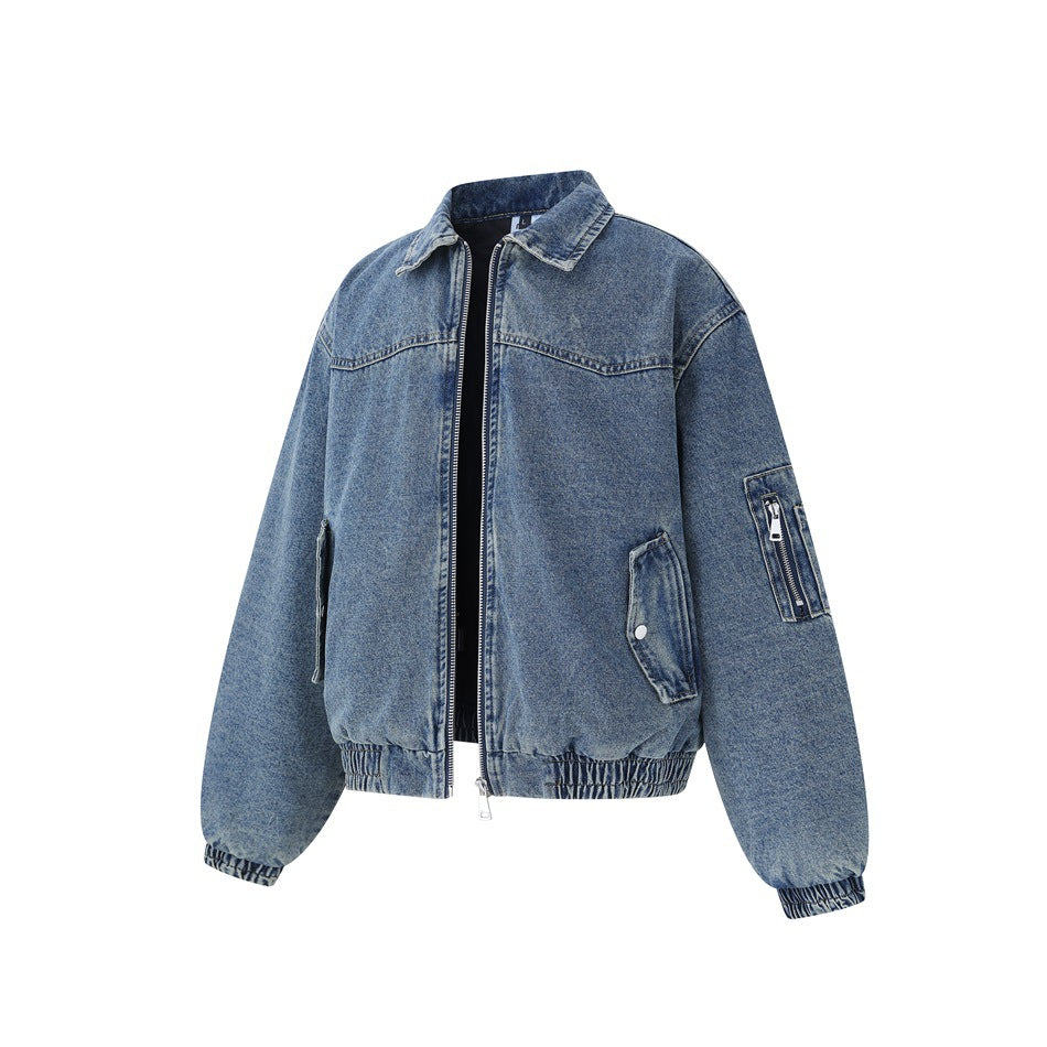 Front view of a blue denim jacket with a zip closure, flap pockets, and a zip pocket on the sleeve.