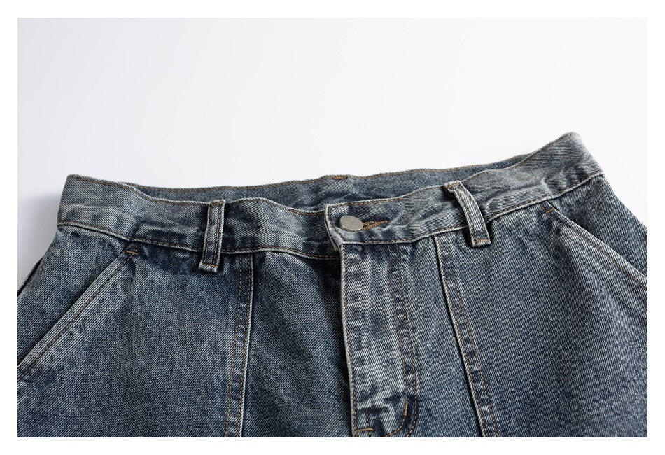 Cropped front view of washed blue-gray jeans showing the waistband, button fly, belt loops, and slanted pockets.