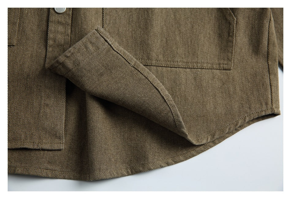 Close-up of an olive-brown jacket showing a flap pocket, button, stitching, and curved hem.